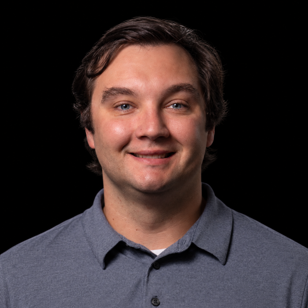 Robert A. Phillips III, smiling in a gray polo shirt against a black background